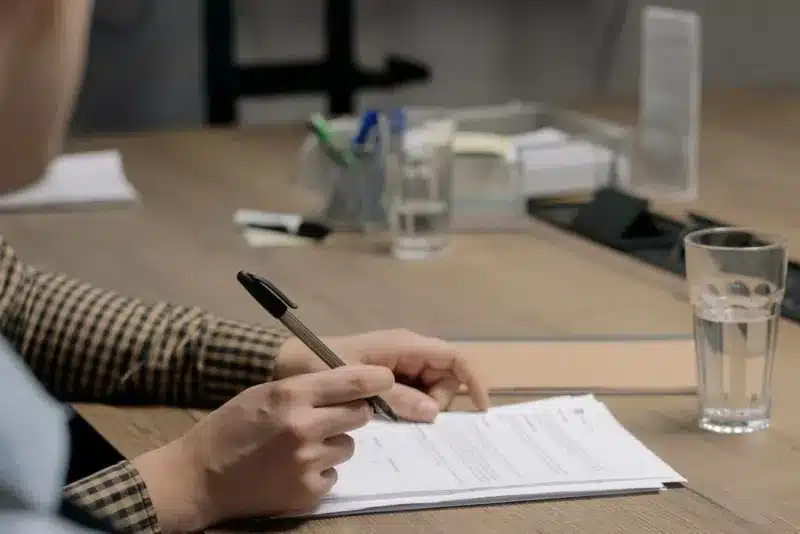 Zzp'er ondertekent een offerte aan houten tafel in kantoor na akkoord met klant