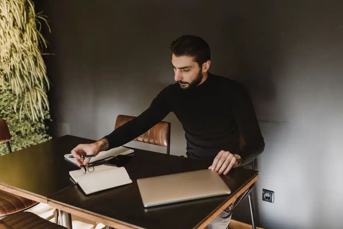 Zelfstandige werkt aan bureau met laptop en schrijft uren op voor zijn urenregistratie