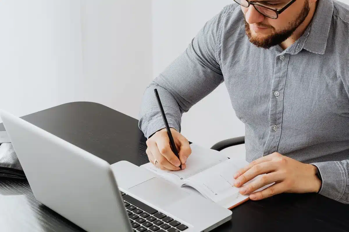 Freelancer werkt achter laptop en noteert declarabele uren en kosten in notitieboek